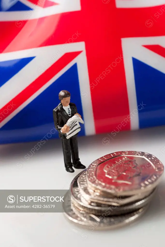 England, North Yorkshire, York. Toy figure of a man stood next to a stack of English 20 pence coins.