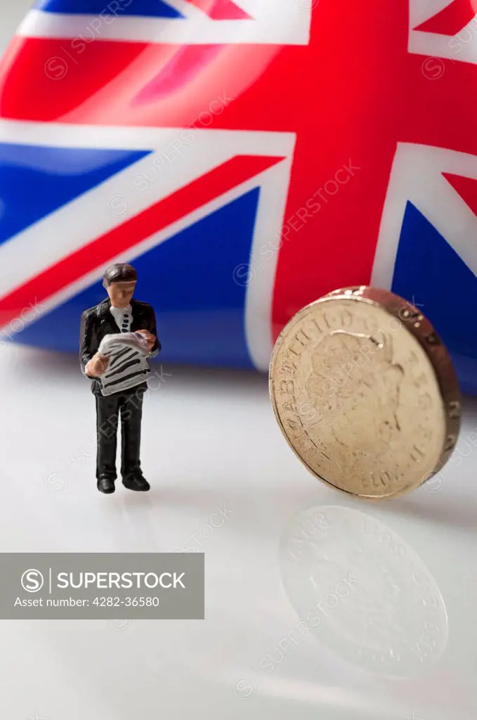England, North Yorkshire, York. Toy figure of a man stood next to an English pound coin.