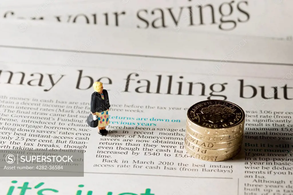 England, North Yorkshire, York. Toy figure of a woman stood next to English pound coins on a page of a financial newspaper.