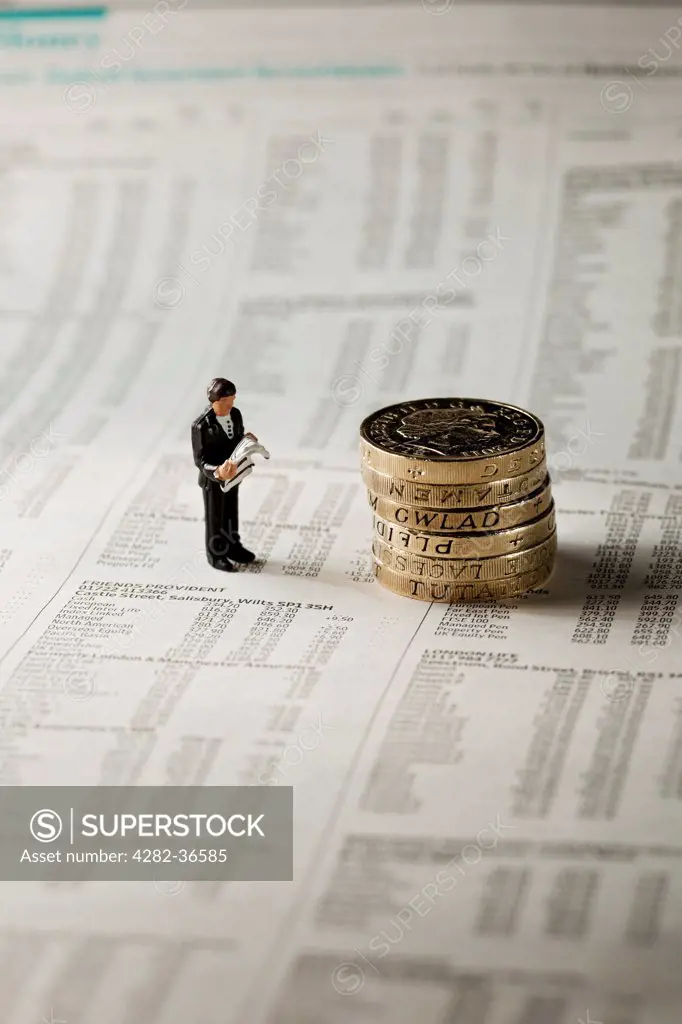 England, North Yorkshire, York. Toy figure of a man stood next to English pound coins on a page of a financial newspaper.