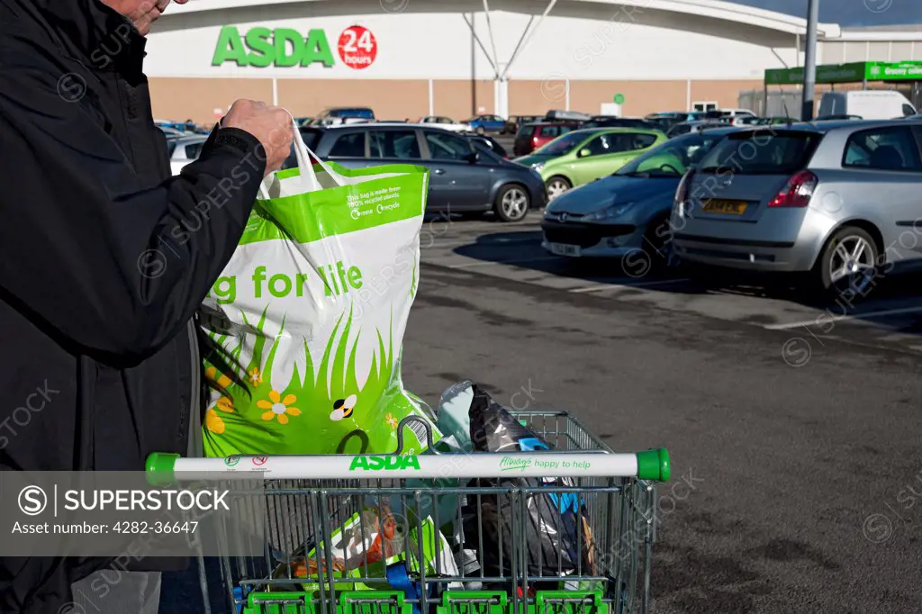 England, North Yorkshire, York. Man with ASDA shopping bags in trolley.