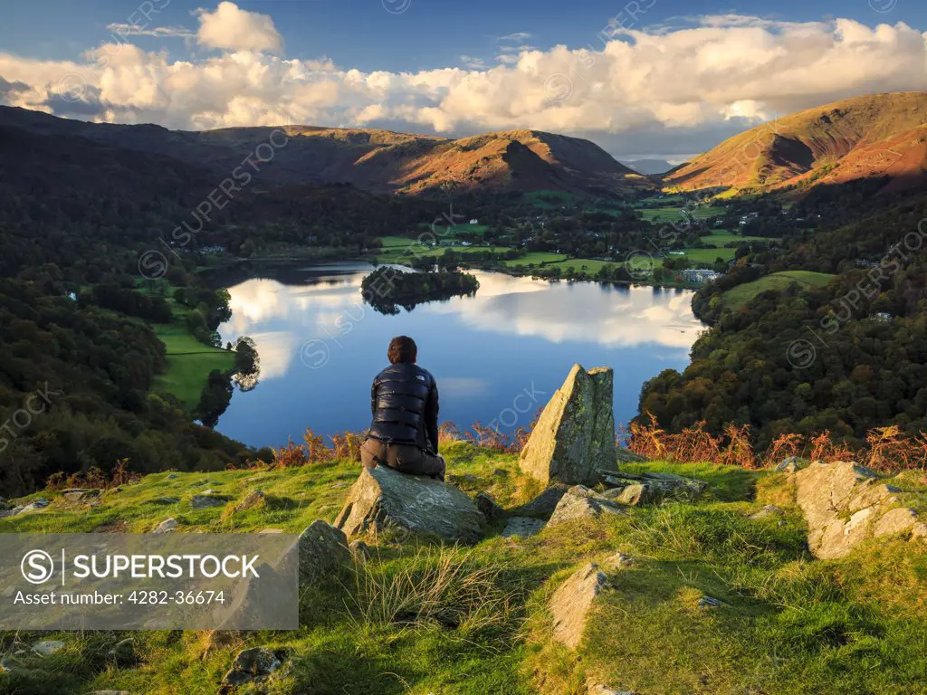 England, Cumbria, Keswick. A walker admires the view of Grasmere from Loughrigg Hill