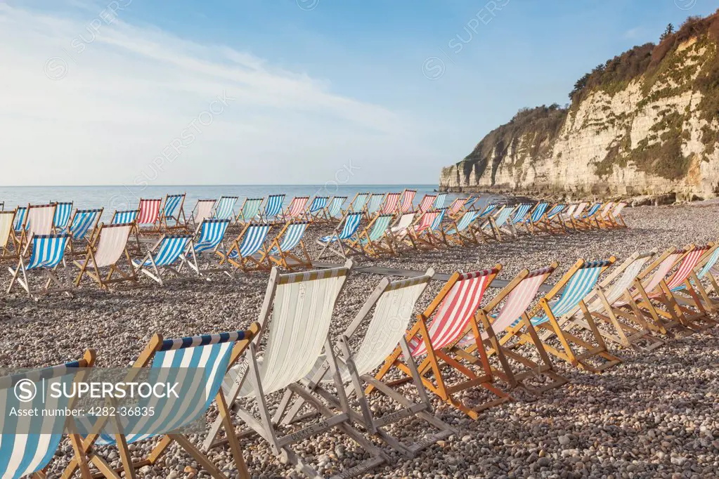 England, Devon, Beer. Deck Chairs in high wind on the beach at Beer.