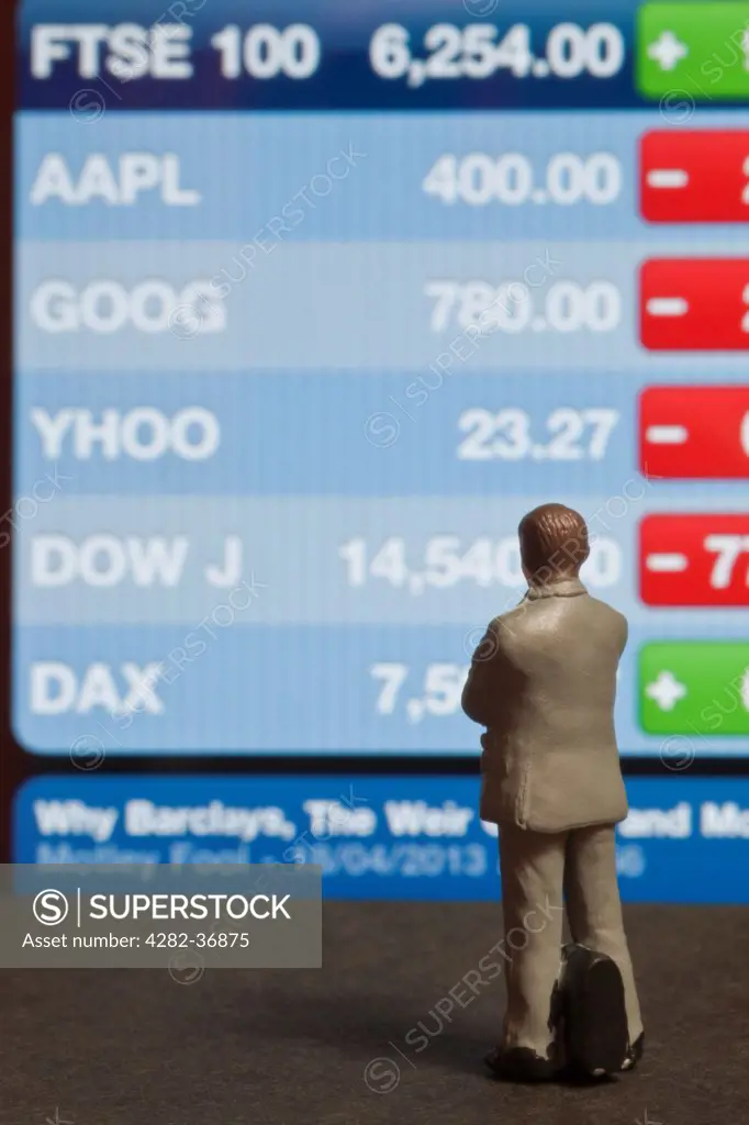 England, Yorkshire, York. Toy business figure looking at FTSE 100 Index screen.