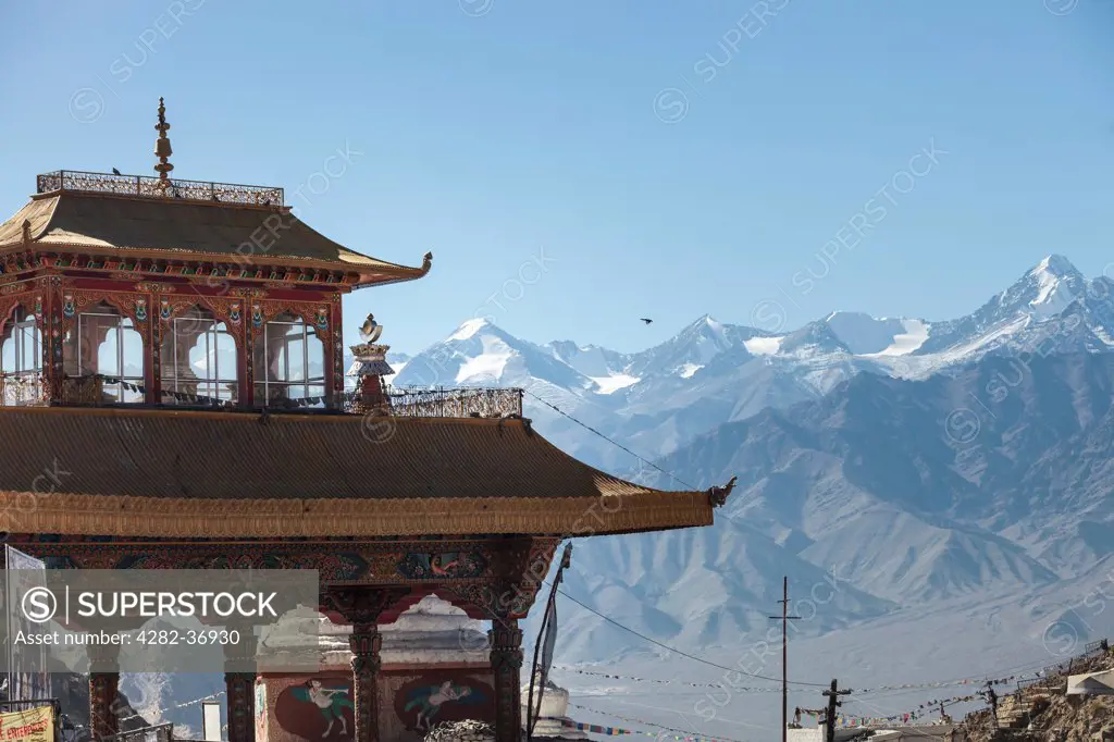 India, Ladakh, Leh. An ornate Buddhist temple with snow covered Himalayas in the background.