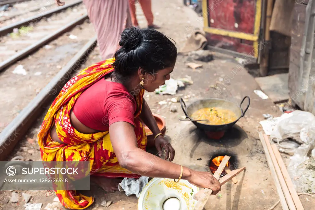 Bangladesh, Dhaka, Dhaka. A Bangladeshi woman cooking on a primitive clay oven at the Karwan slum in Dhaka.