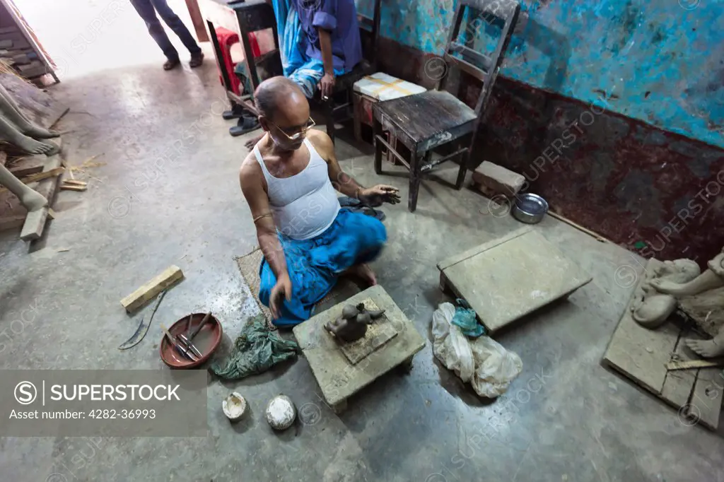 Bangladesh, Dhaka, Dhaka. Bangladeshi craftsman modelling little Buddha statues in a small workshop.