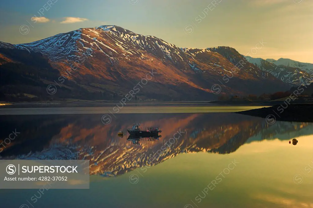 Scotland, Highland, Glen Coe. Mountains and boat reflected in Loch Leven.