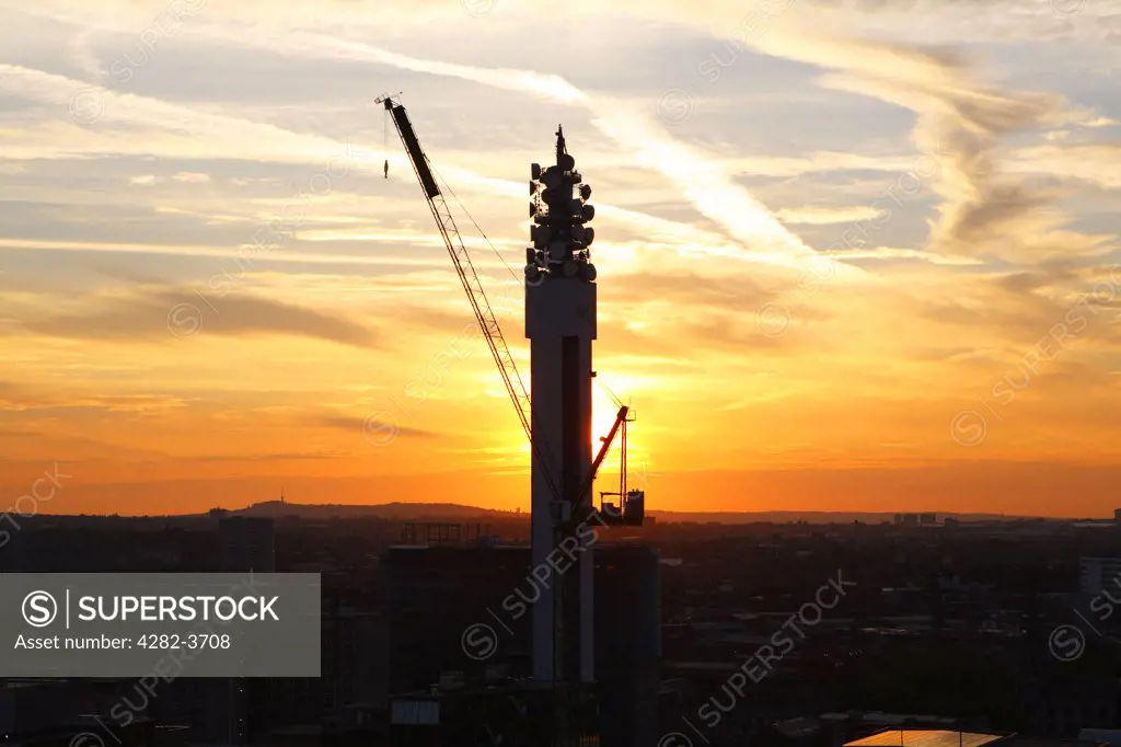 England, West Midlands, Birmingham. A crane in front of the BT Tower in Birmingham at sunset.