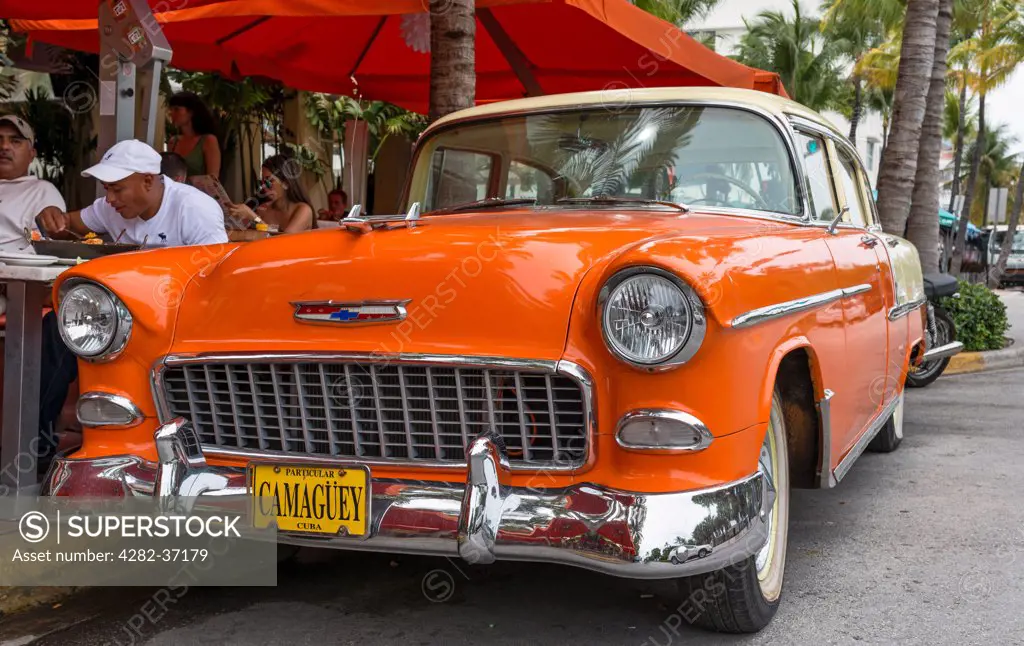 USA, Florida, Miami. An old orange car parked on Ocean Drive in the South Beach area of Miami.