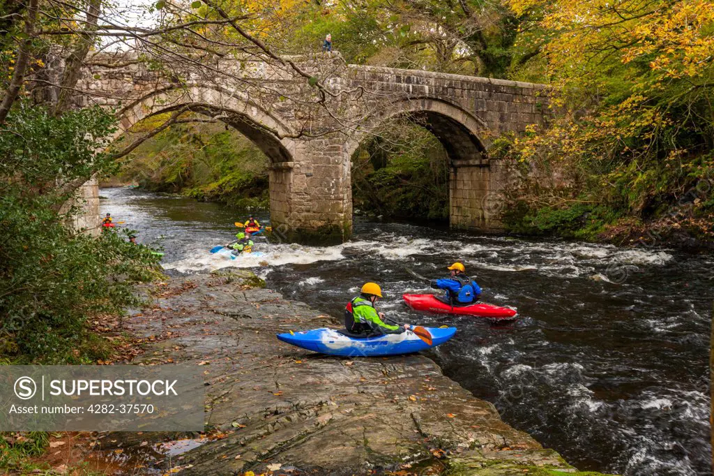 England, Devon, Holne. People kayaking on the river Dart near New Bridge in the Dartmoor National Park.