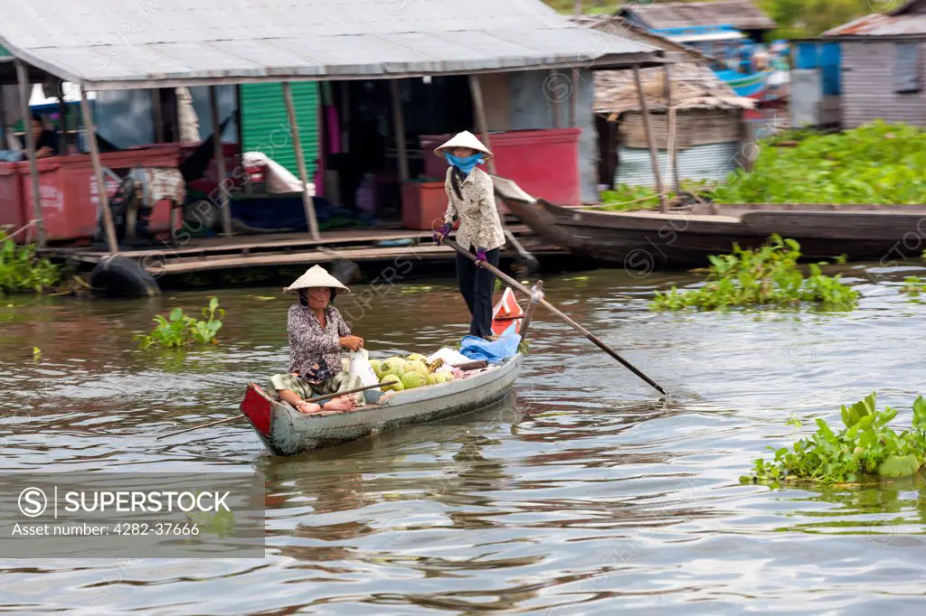 Cambodia, Kampong Chhnang, Phumi Kandal. A woman drives her boat on the Tonle Sap floating village.