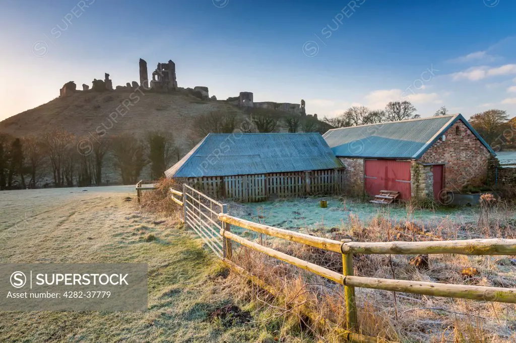England, Dorset, Corfe Castle. A view towards the ruins of Corfe Castle with a farm shed in the foreground.