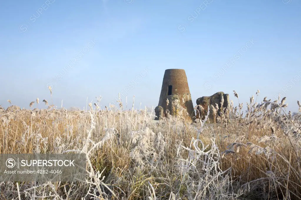 England, Norfolk, near Horning. The windmill and gatehouse of St Benets Abbey on the Norfolk Broads, surrounded by frozen marsh land and reeds following a winter Hoarfrost.