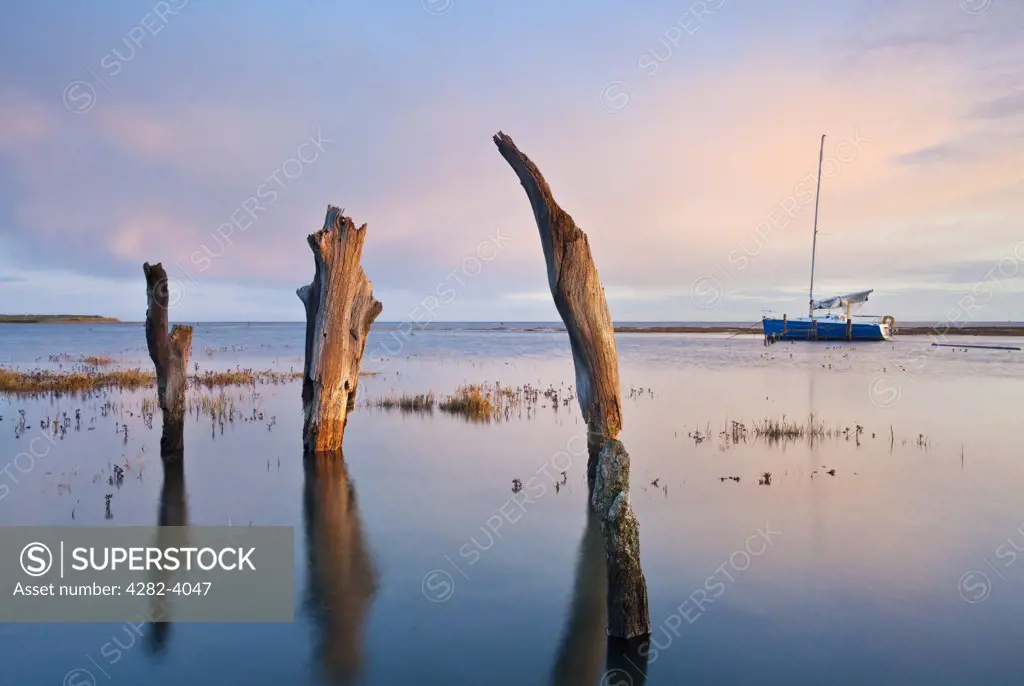 England, Norfolk, Thornham. Thornham Harbour and the remains of an ancient wooden pier at high tide on the North Norfolk Coast.
