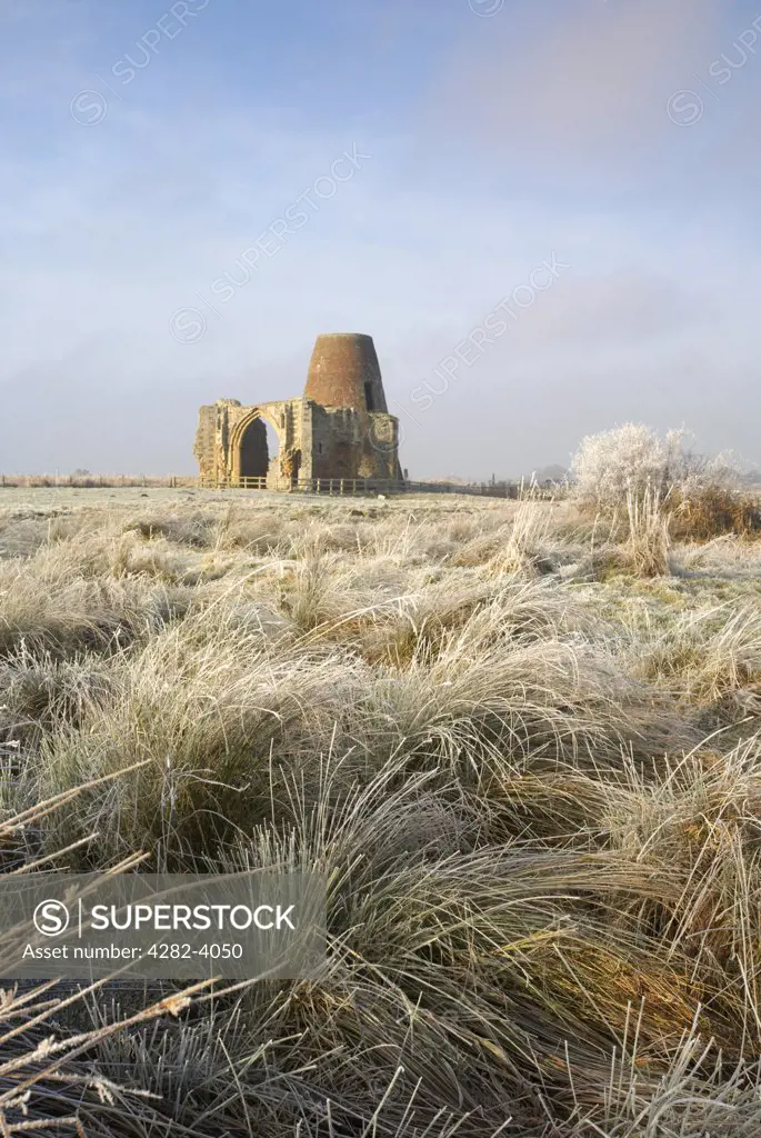 England, Norfolk, near Horning. The windmill and gatehouse of St Benets Abbey on the Norfolk Broads, surrounded by frozen marsh land and reeds following a winter Hoarfrost.