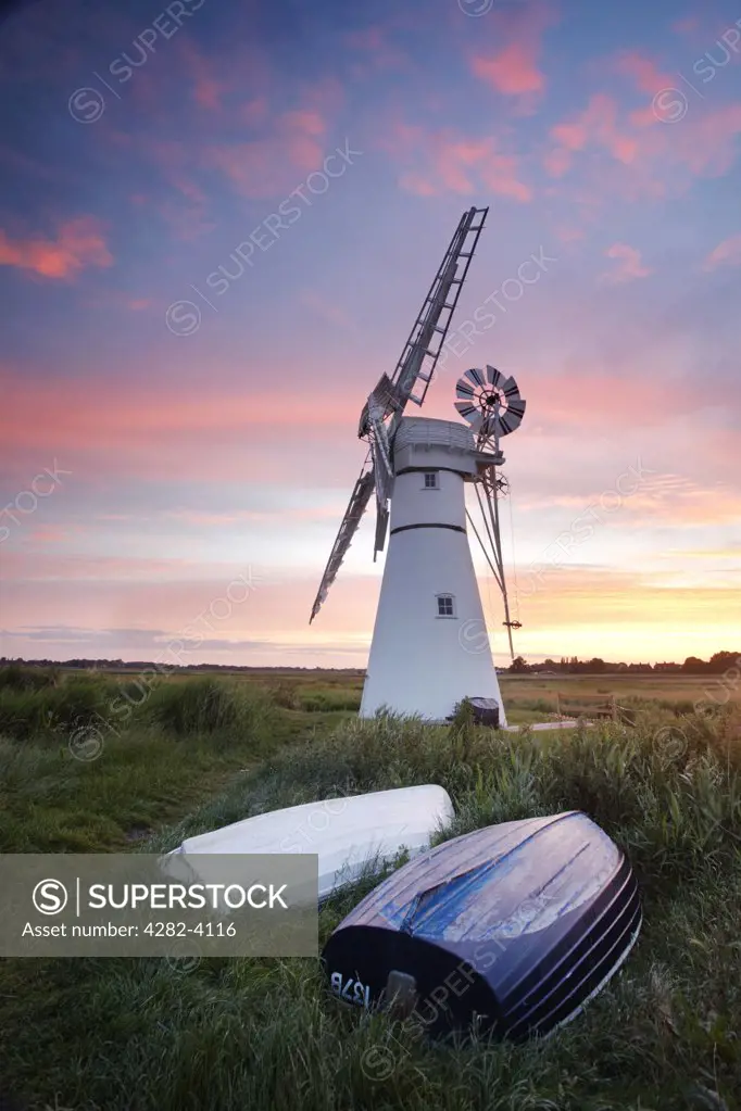 England, Norfolk, Thurne. Sunrise over upturned boats by Thurne Mill standing at the entrance to Thurne Dyke on the Norfolk Broads.