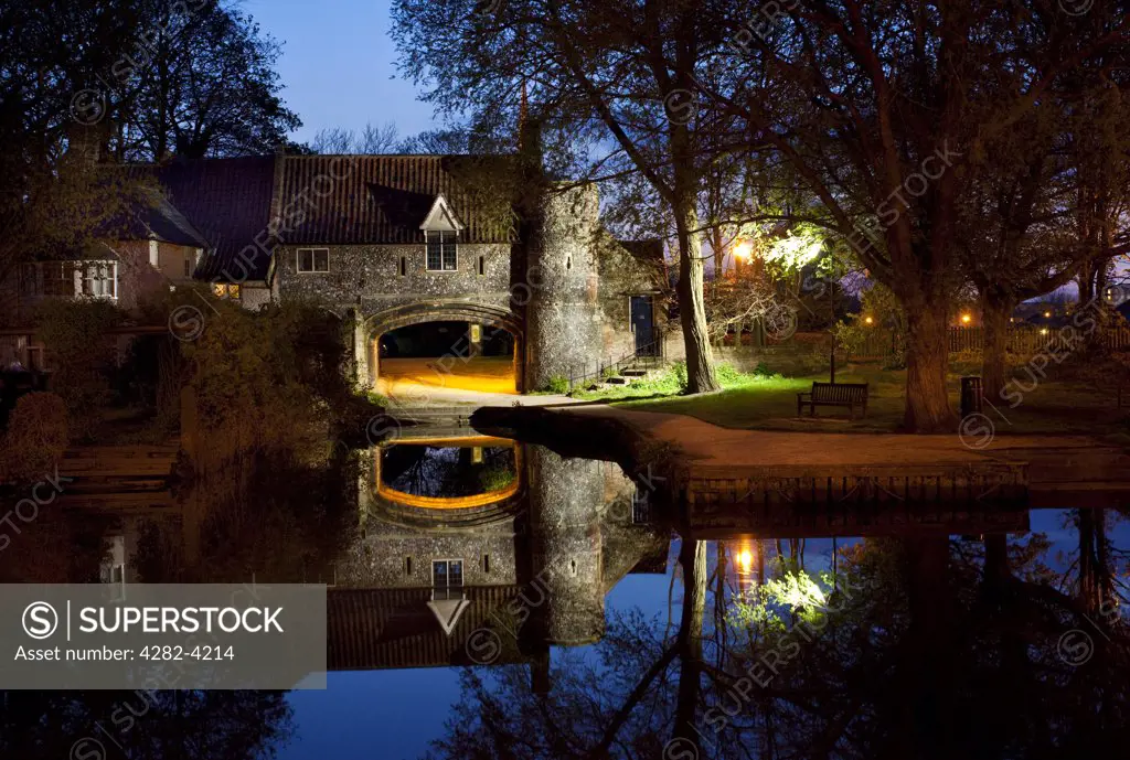 England, Norfolk, Norwich. Pulls Ferry, once a 15th century watergate on the River Wensum, illuminated at night.