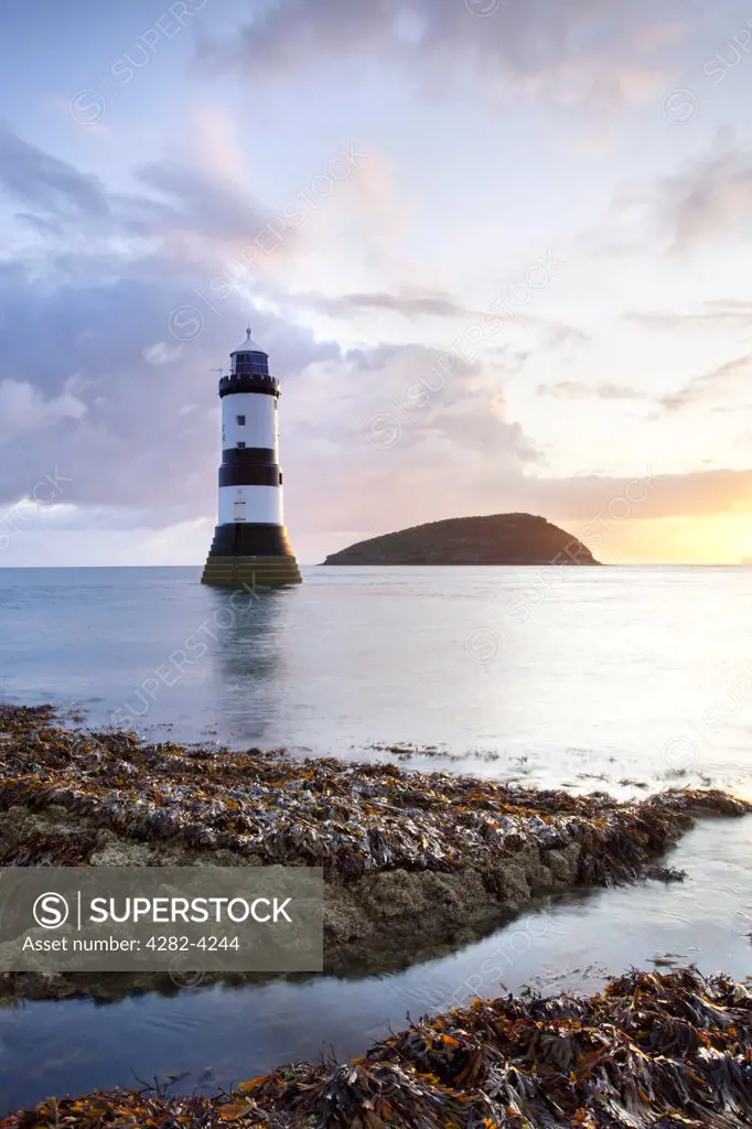 Wales, Isle of Anglesey, Penmon. A view of Penmon Lighthouse and Puffin Island at dawn on the coast of Anglesey in North Wales.