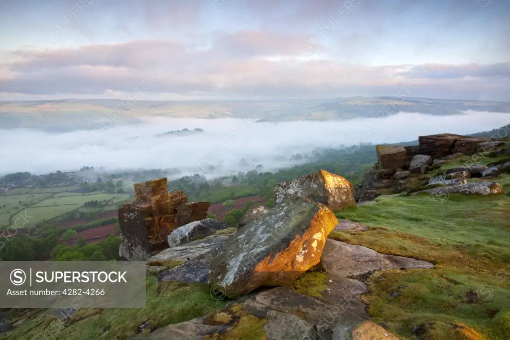 England, Derbyshire, Curbar Edge. Mist over the village of Calver viewed at first light from Curbar Edge in the Peak District National Park.