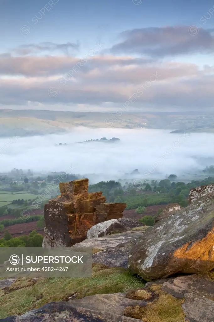 England, Derbyshire, Curbar Edge. Mist over the village of Calver viewed at first light from Curbar Edge in the Peak District National Park.