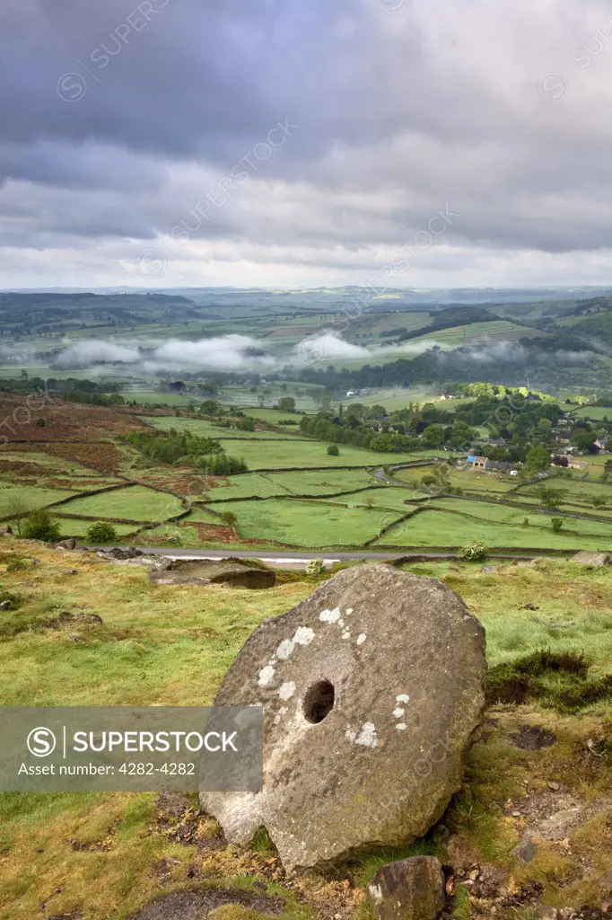 England, Derbyshire, Curbar Edge. View at dawn from an abandoned millstone on Curbar edge to low lying mist in the valley below.