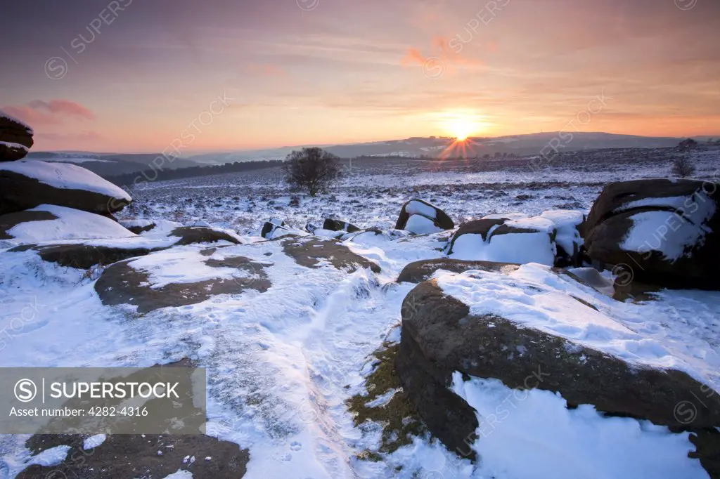 England, Derbyshire, Peak District National Park. Sunset viewed from snow covered Over Owler Tor in the Peak District National Park.