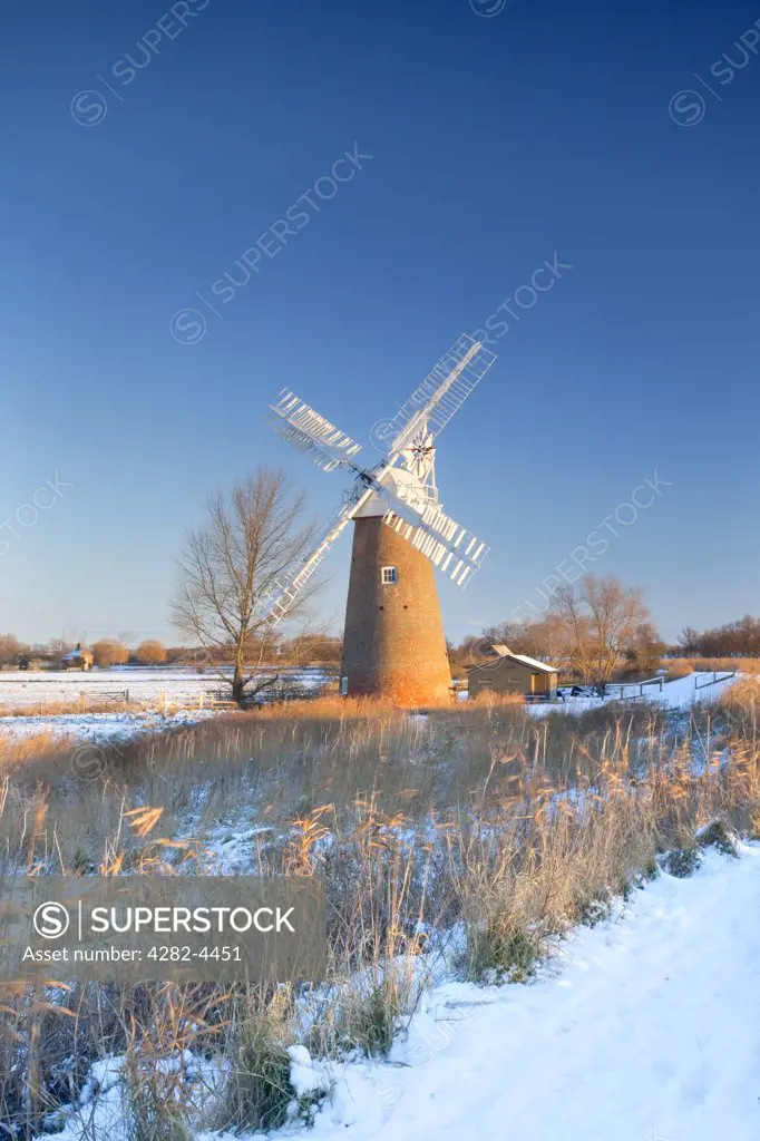 England, Norfolk, near Hardley Street. Snow on the ground around the newly restored Hardley Drainage Mill, originally built in 1874, on the Norfolk Broads.