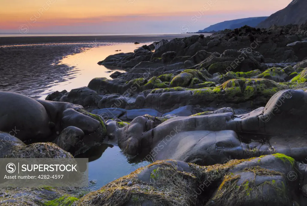 England, Cornwall, Bude. Sun setting over rocks and cliffs at Sandymouth beach. It is a large pebbled beach with lots of sand at lower tides when it connects up with other Bude beaches.