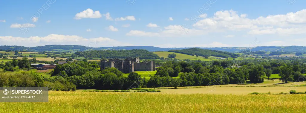 Wales, Monmouthshire, Raglan. A view over a wheat field toward the 15th Century ruin of Raglan Castle.