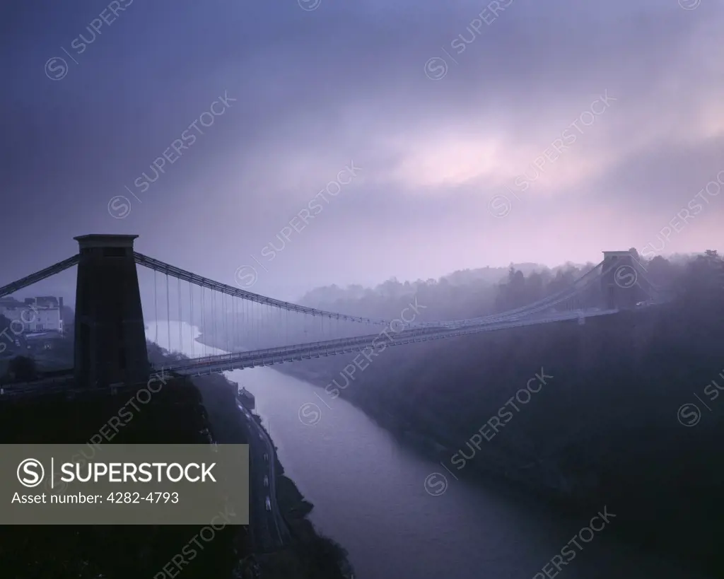 England, Bristol, Bristol. Clifton Suspension Bridge over the River Avon in winter fog just after sunset.