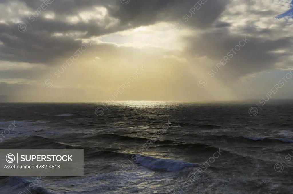 England, Cornwall, Coombe. Sunlight breaking through clouds over Bude Bay off the North Cornwall coast.