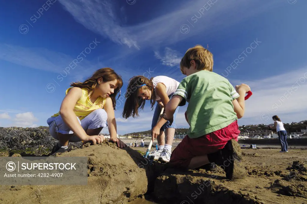 England, Devon, Westward Ho!. Three preteen children playing in the sun on the beach at Westward Ho in Devon.