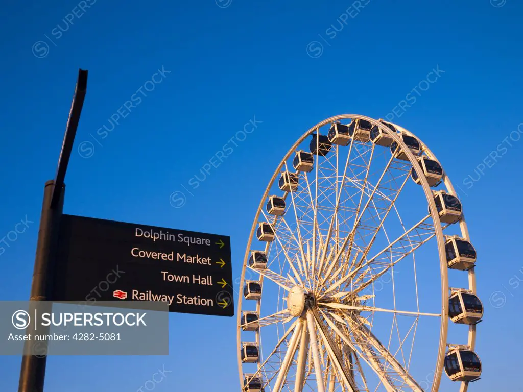England, Somerset, Weston-super-Mare. The Wheel of Weston and signpost on the seafront of Weston-super-Mare at sunset.