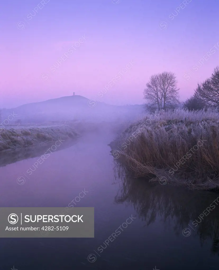 England, Somerset, Glastonbury. The River Brue on South Moor on the Somerset Levels at Glastonbury with Glastonbury Tor in the distance, Somerset.