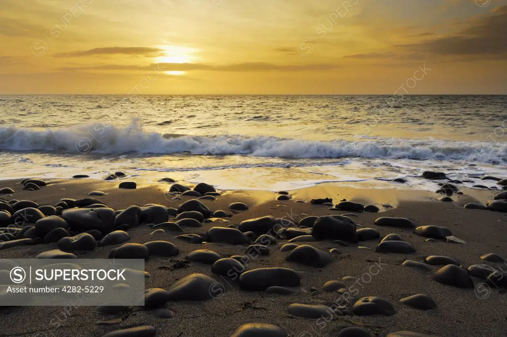England, Devon, Westward Ho!. Waves washing onto the pebbled beach during sunset at Westward Ho! on the North Devon coast.