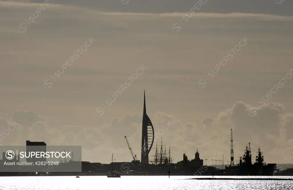 England, Hampshire, Portsmouth. A silhouette of Spinnaker Tower, a Royal Navy warship, HMS Victory and Portsmouth Harbour seen from Portchester Castle.