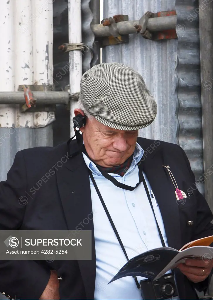 England, West Sussex, Goodwood Revival. Man reading racing schedule at Goodwood Revival.