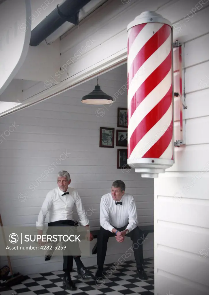 England, West Sussex, Goodwood Revival. Men sitting in old fashioned barber shop at Goodwood Revival.