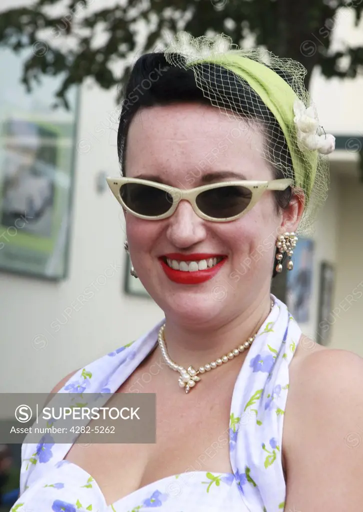 England, West Sussex, Goodwood Revival. Lady with red lipstick, hair net, and winged eyeglasses at Goodwood Revival.