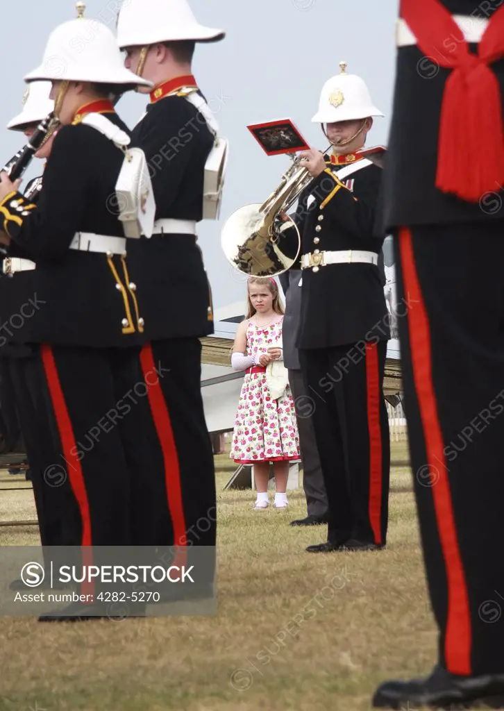 England, West Sussex, Goodwood Revival. Girl is flower dress listening to Military band at Goodwood Revival.