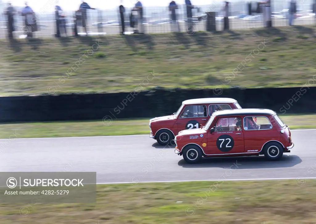 England, West Sussex, Goodwood Revival. Red Mini Coopers racing at Goodwood Revival.