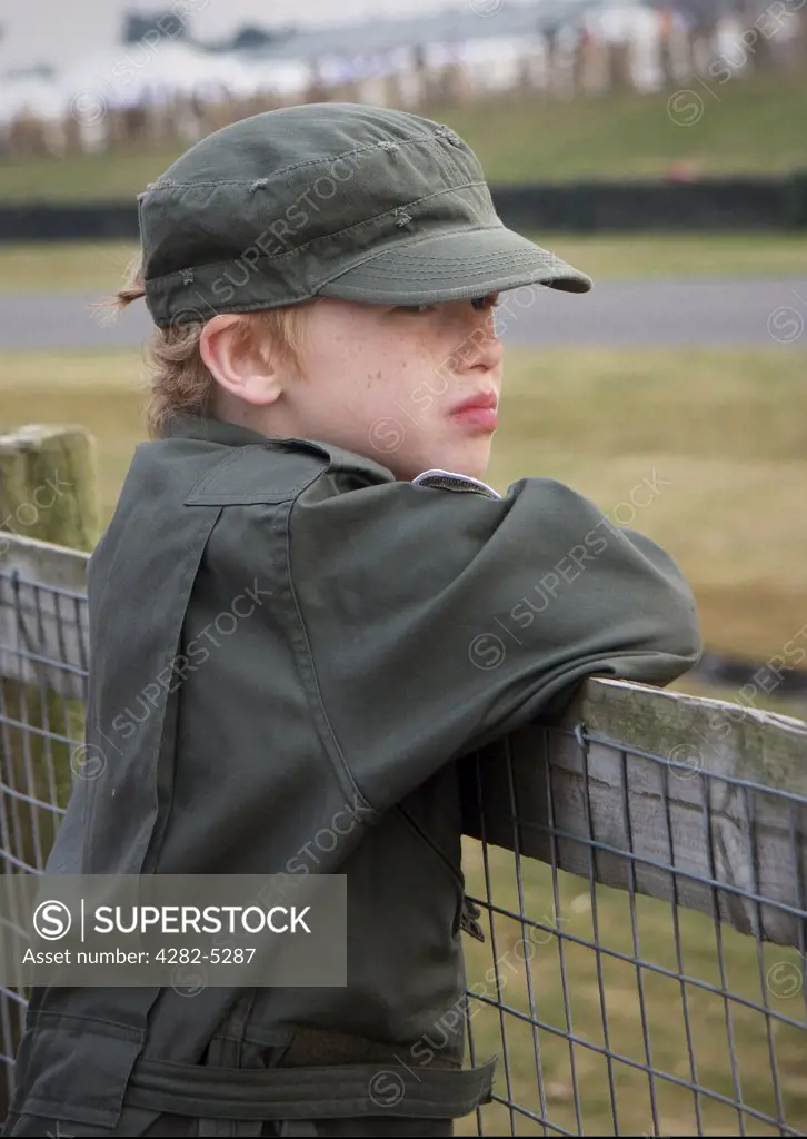 England, West Sussex, Goodwood Revival. Young boy in jumpsuit watching car races at Goodwood Revival.