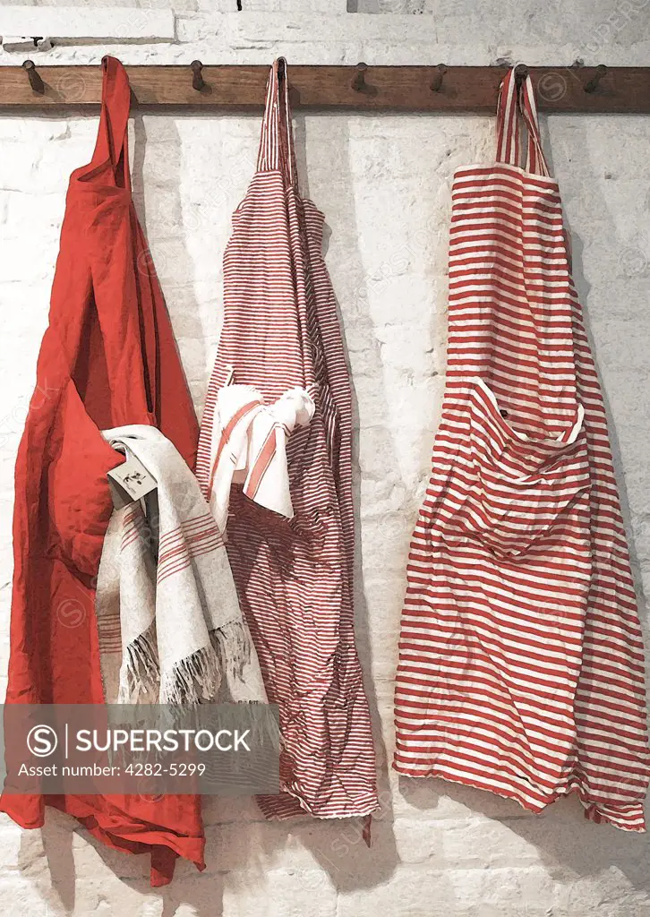 England, London, Hampstead Heath. Red kitchen aprons hanging on hooks.