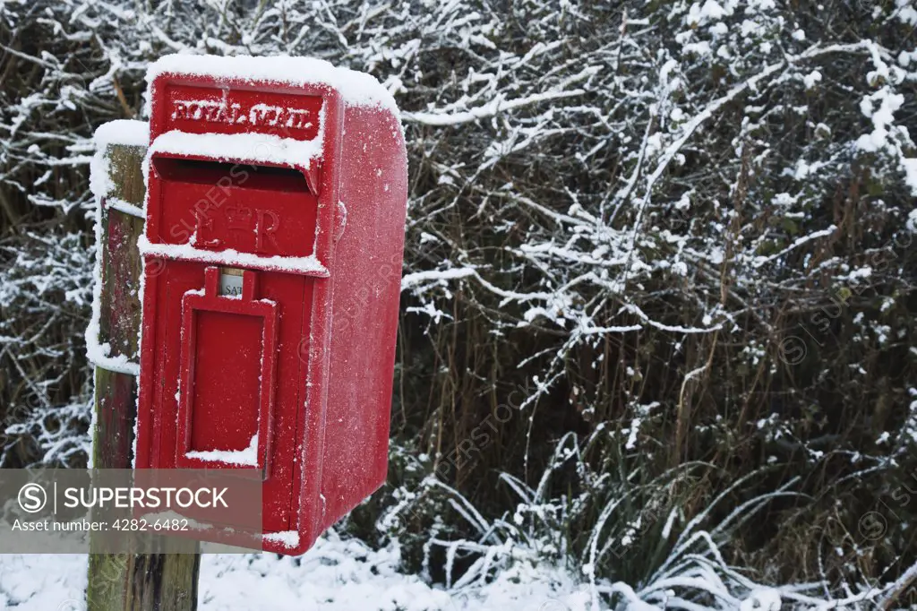 England, Wiltshire, Brinkworth. A small rural red post box covered in snow.