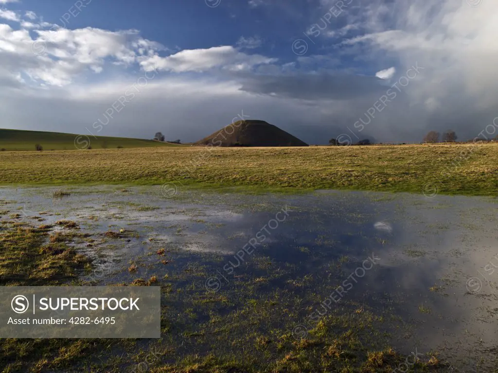 England, Wiltshire, near Avebury. Silbury Hill, the tallest prehistoric human-made mound in Europe, viewed across a flooded field.