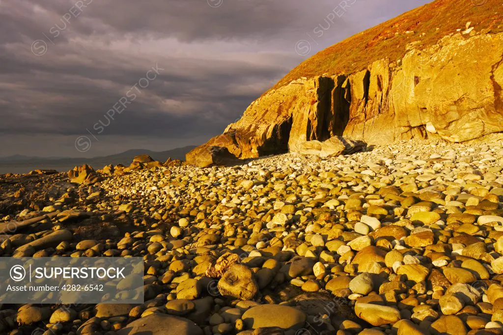 Wales, Gwynedd, near Llwyngwril. Storm light over a stoney beach near Llwyngwril in the Snowdonia National Park.
