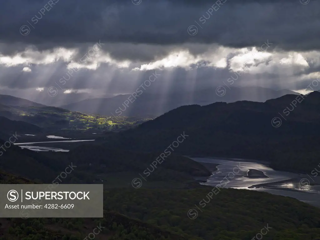Wales, Gwynedd, Mawddach Estuary. Rays of sunshine through storm clouds over the river Mawddach estuary.