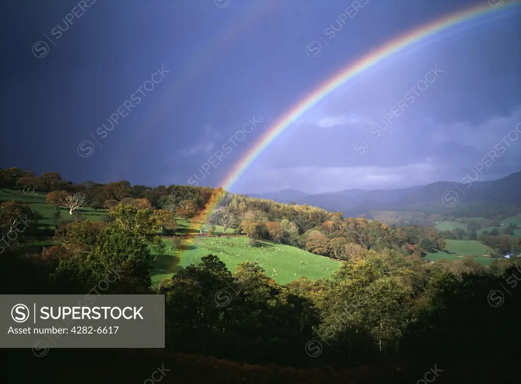 Wales, Denbighshire, Near Llangollen. Storm light with rainbow against dark skies over Welsh hills.