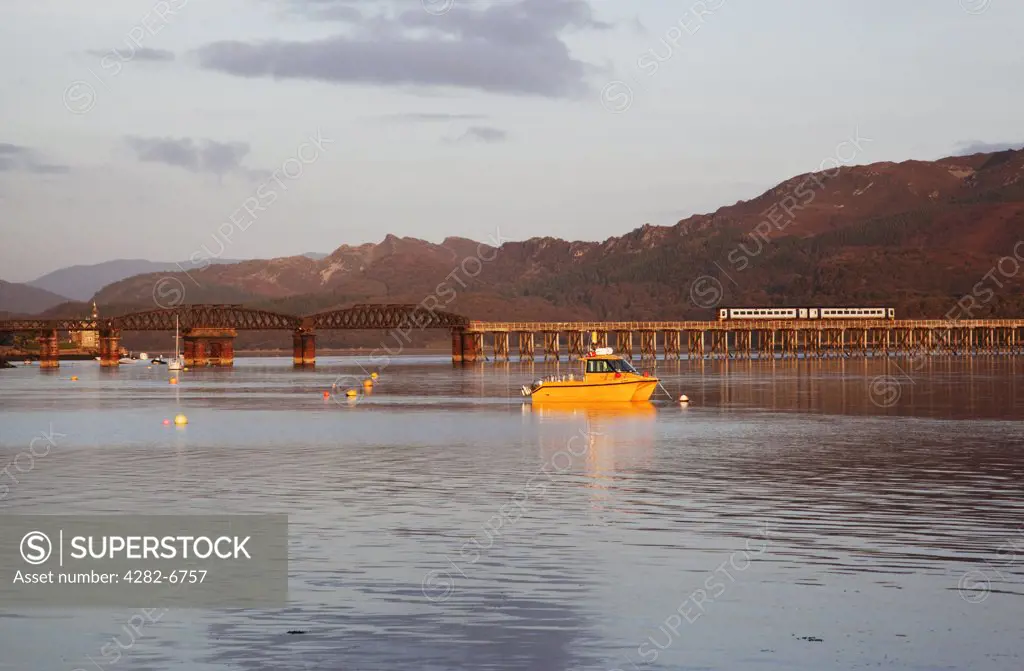 Wales, Gwynedd, Barmouth. Barmouth harbour and railway bridge - a train is crossing the bridge.